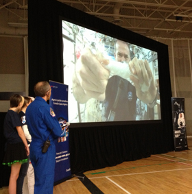 Hadfield wrings out a wet cloth to demonstrate surface tension.