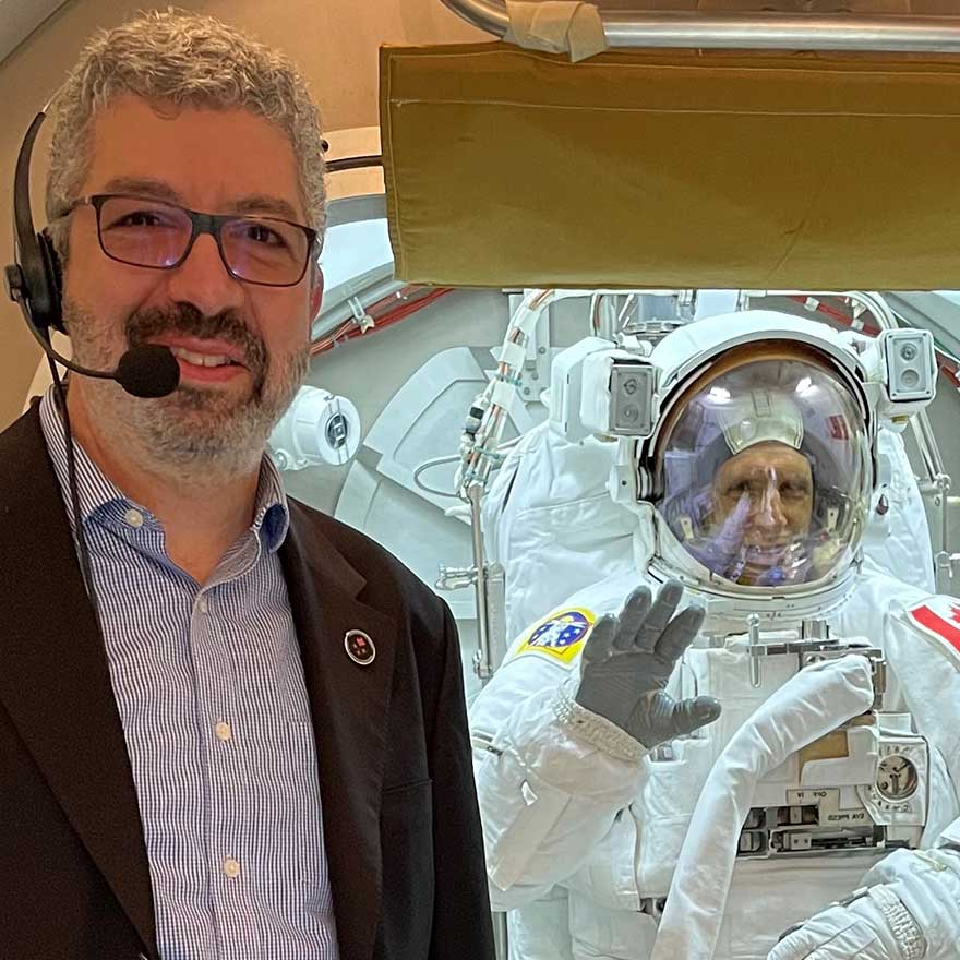 Raffi Kuyumjian poses in front of Joshua Kutryk, who is wearing a spacesuit.