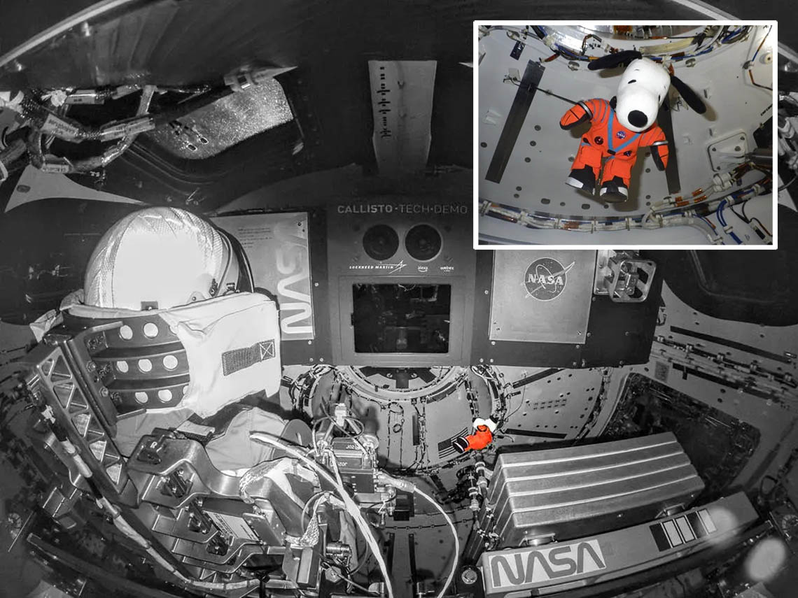 A Snoopy plushie floats in a custom orange spacesuit abord the Orion capsule.