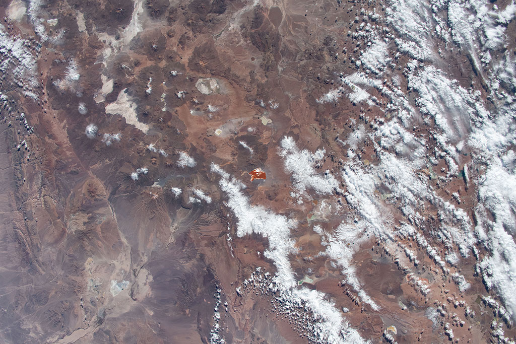 Laguna Colorada is a shallow salt lake in Bolivia, close to the border with Chile. It can easily be seen from space due the reddish color of its waters, caused by red sediments and pigmentation of some algae. The lake also contains borax islands, which appear white and contrast with the water. This photo was taken by David Saint-Jacques from the International Space Station. (Credit: Canadian Space Agency/NASA)