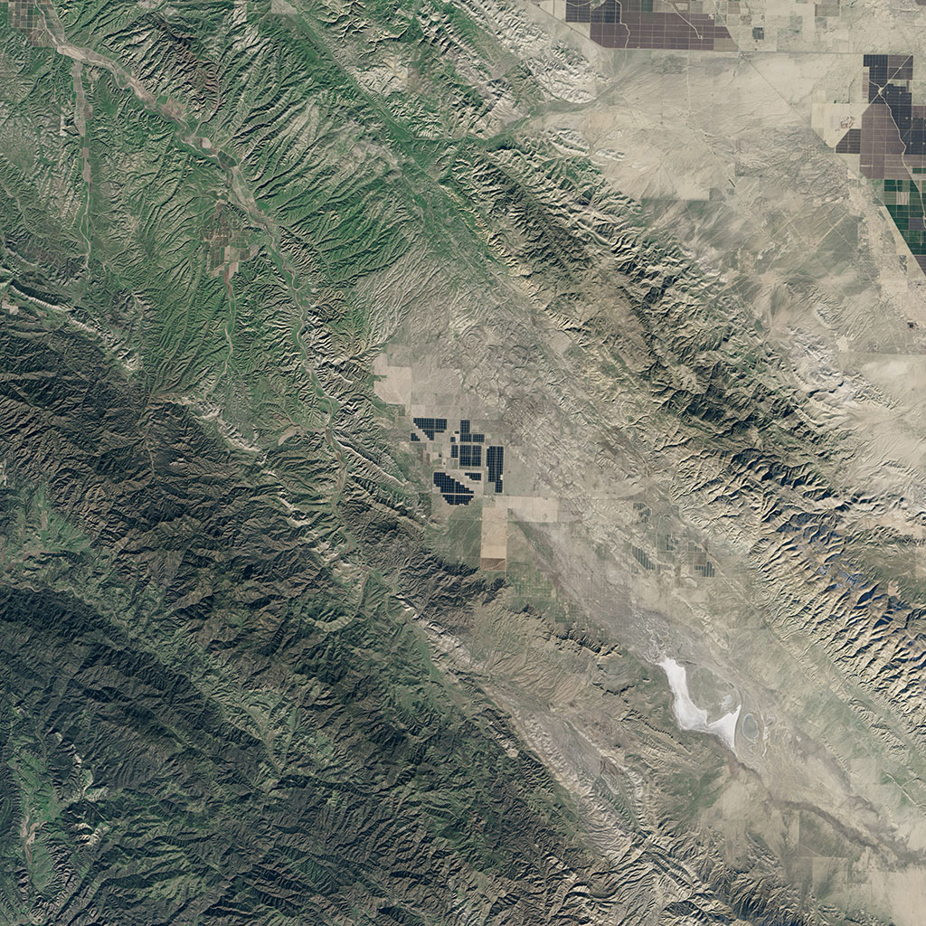 Topaz Solar Farm, in southern California, is one of the largest photovoltaic power plants in the world. At 925.6 square kilometers, the facility is about the equivalent of 4,600 football fields. This image was captured in 2015 by the American Landsat 8 satellite. Solar arrays appear gray and charcoal. The surrounding farmland and grasslands appear brown and green. (Credit: USGS/NASA Landsat)
