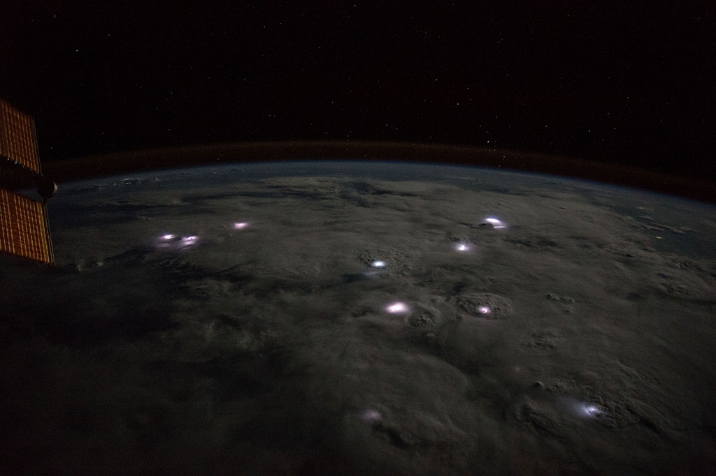 The tiny white dots that we see through the clouds in this photo taken from the International Space Station are actually thunderstorms over Africa. (Credit: NASA)