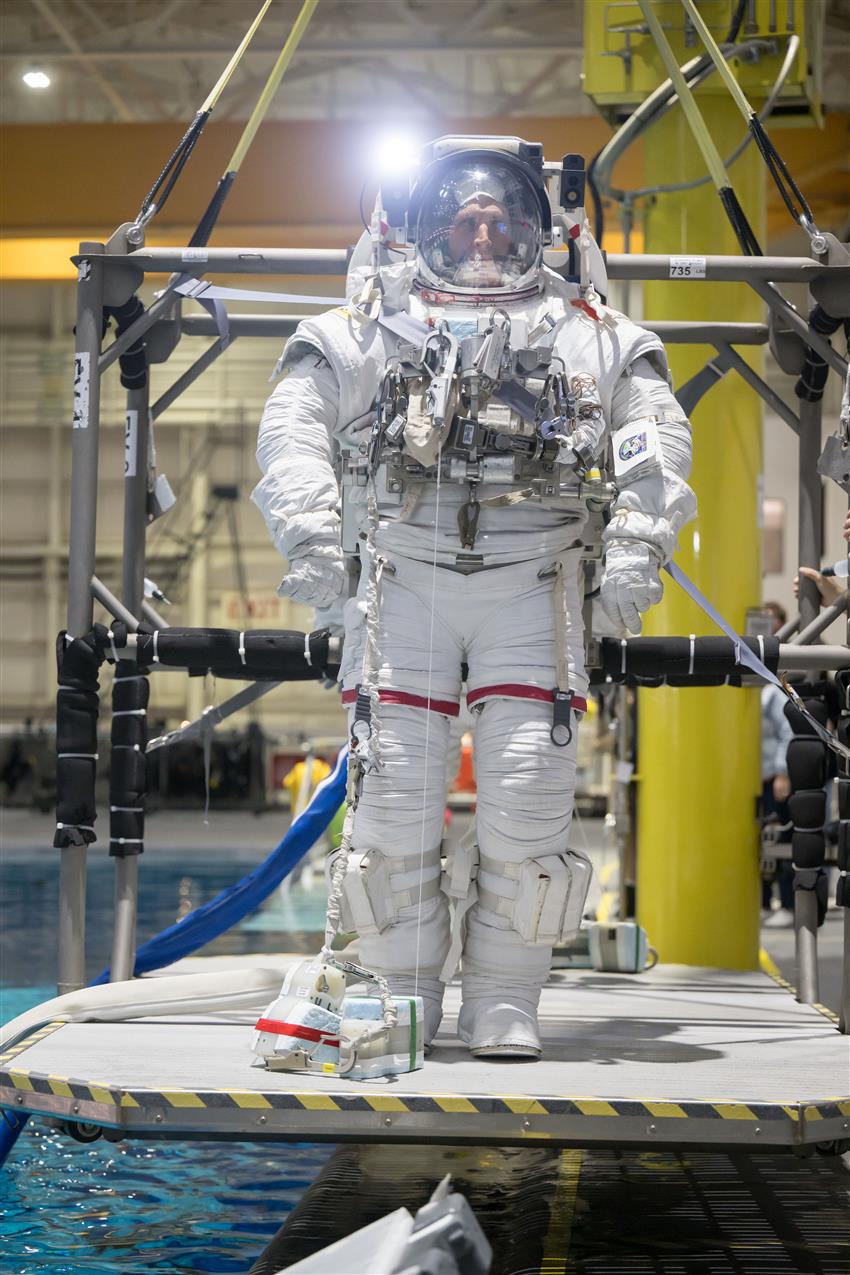 Joshua is standing on a platform wearing his spacesuit. 