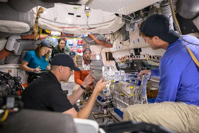 Les quatre astronautes sont assis dans la maquette.