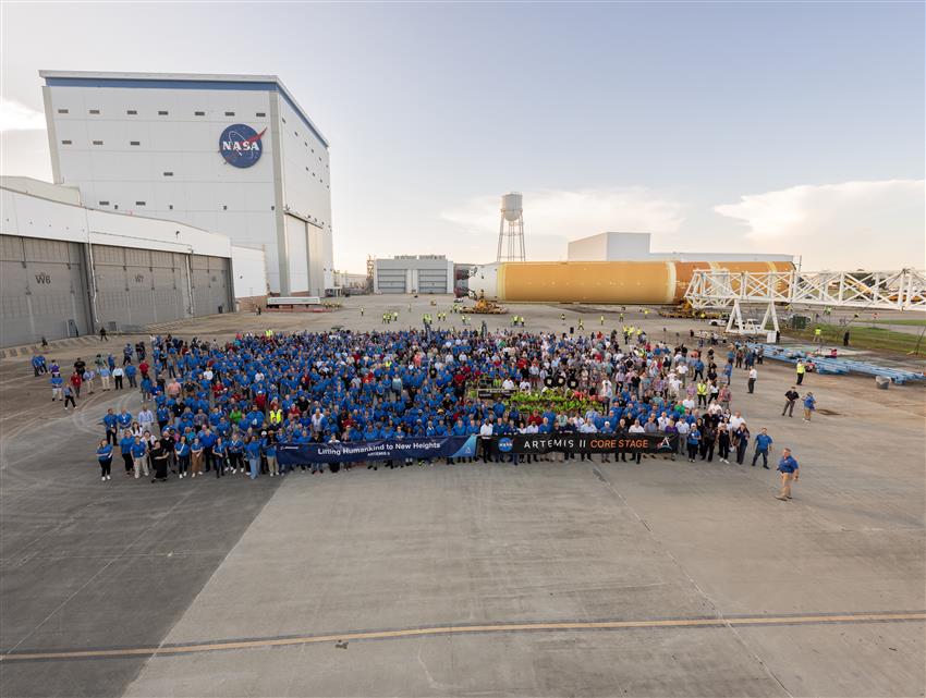 Photo de groupe de centaines de personnes. L'étage principal du lanceur SLS se trouve derrière.
