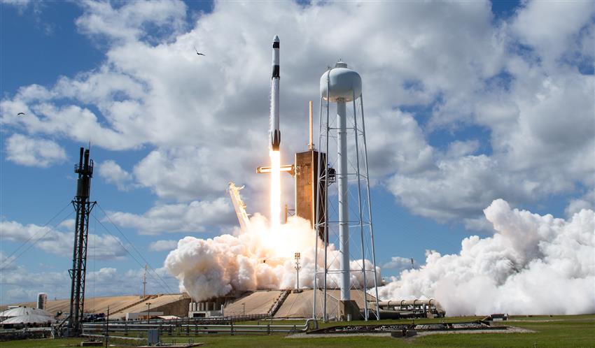 Une fusée décollant du centre spatial Kennedy. La combustion du réacteur produit une lumière vive et beaucoup de fumée