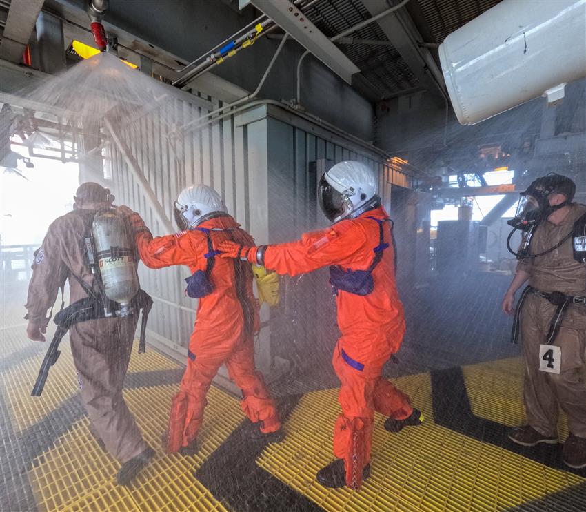 Three people walking through water being sprayed from the ceiling. 