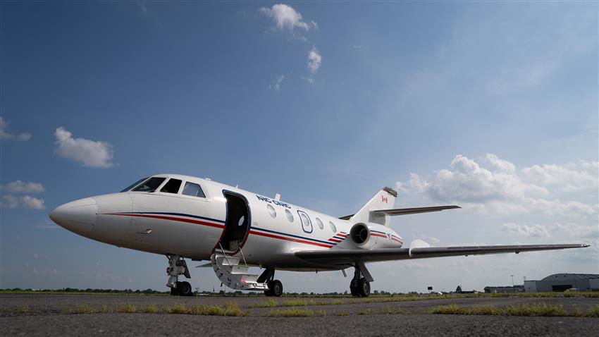 A small plane is on a landing strip with an airport in the background