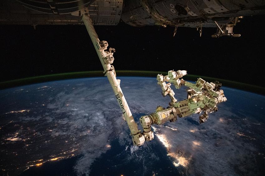 Dextre et Canadarm2 sont attachés l'un à l'autre. La péninsule arabique vue de l'espace est en arrière-plan.