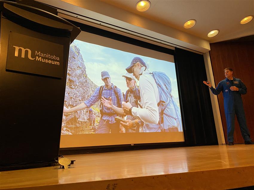 Jeremy on stage pointing at a photo on a large screen.