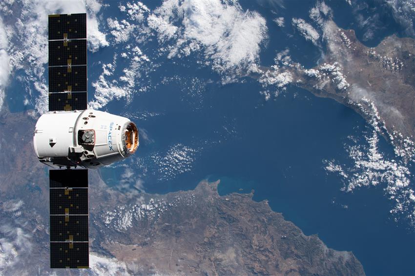 The SpaceX cargo spacecraft Dragon with Earth in the background.