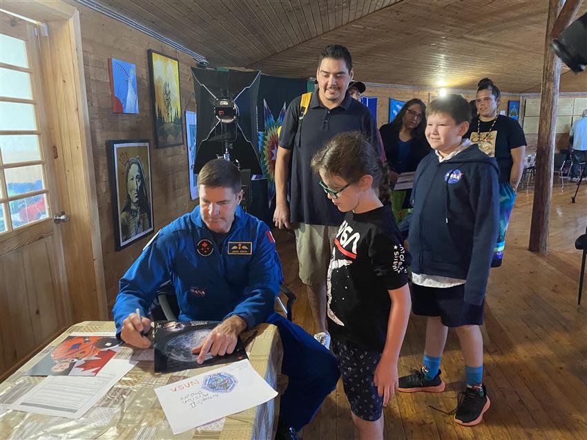 Jeremy signs a poster for two children and some adults.