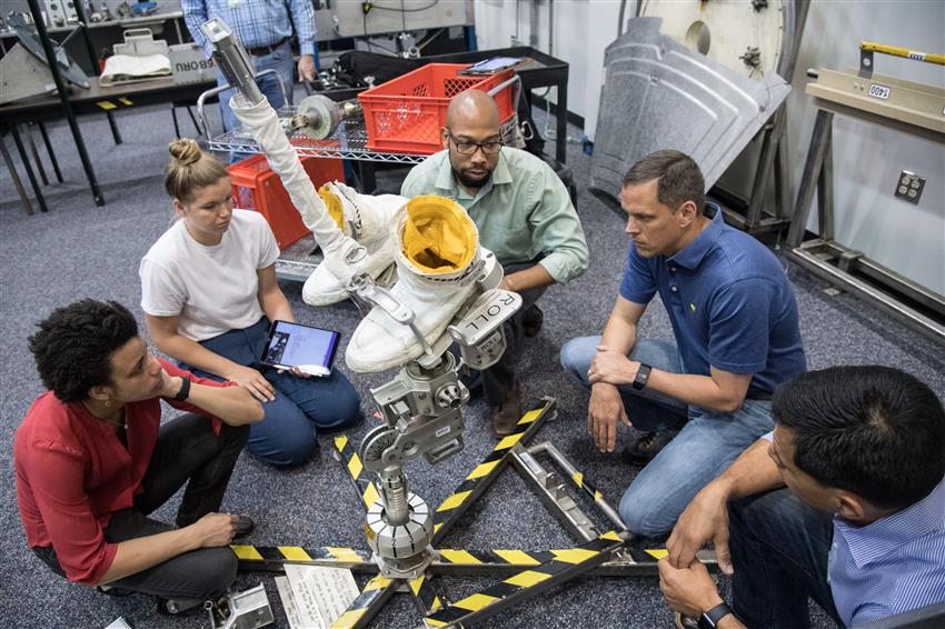 Jenni, Jessica, Bob, Frank and an instructor around a replica of an ISS tool