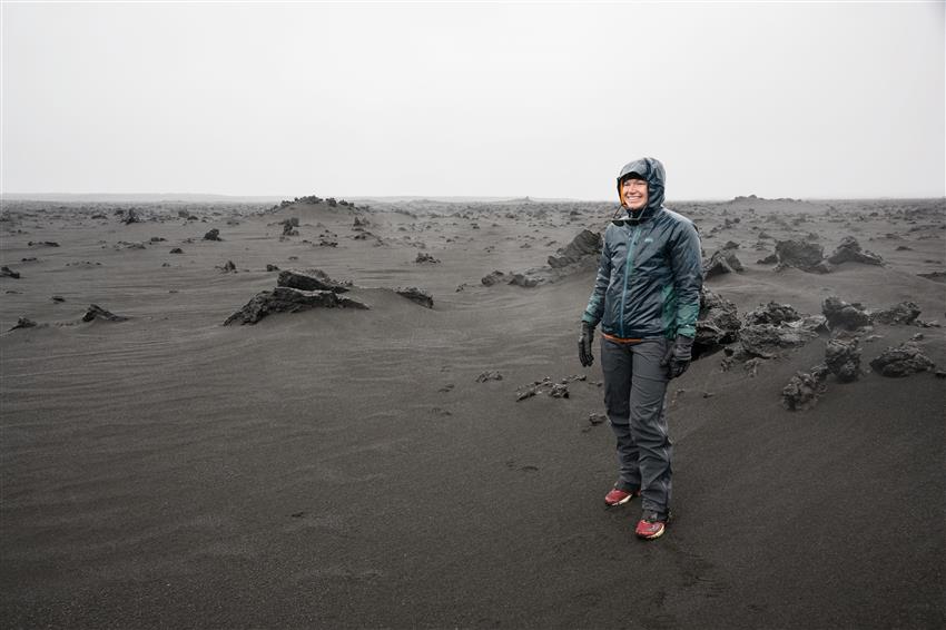 Jenni debout dans un désert de roches volcaniques noires.