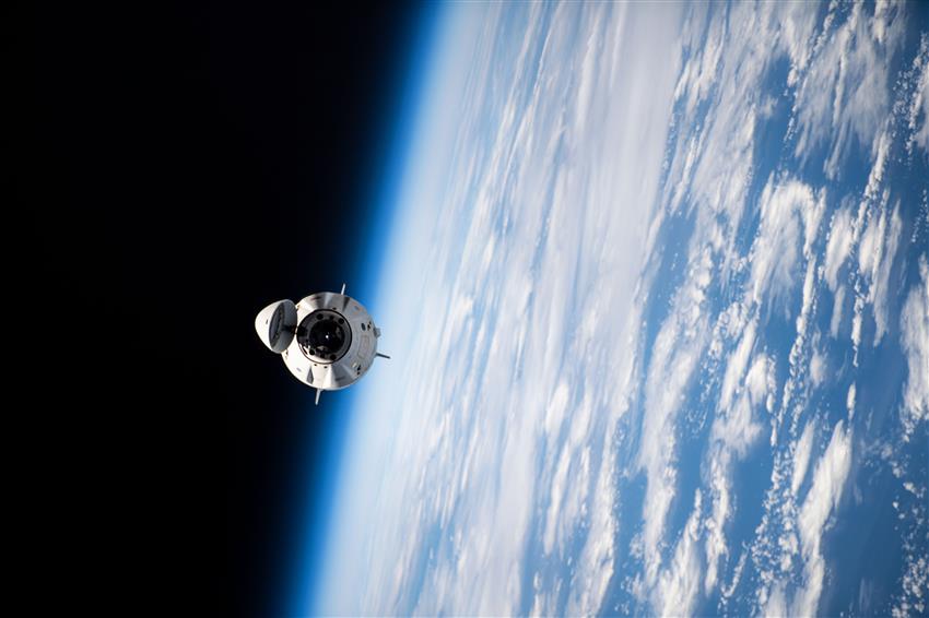 The spacecraft has its hatch open, with Earth in the background.