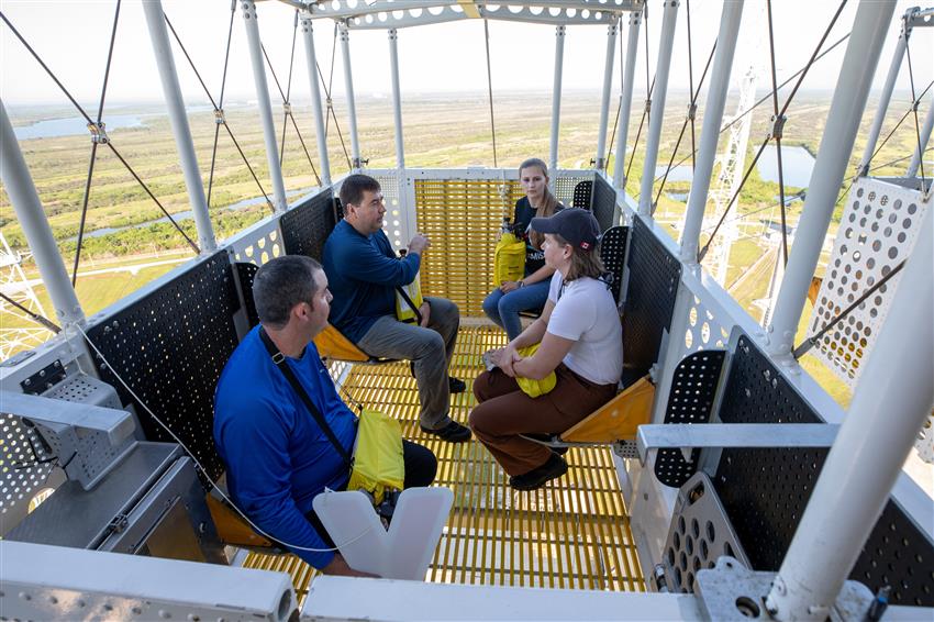 Jenni sits in an emergency egress basket with three other people.