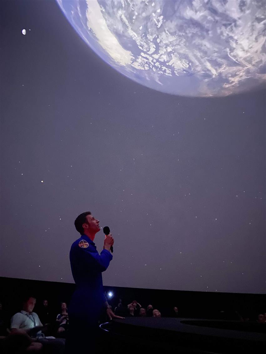 Joshua is delivers his presentation with Earth seen in the background on the big screen.