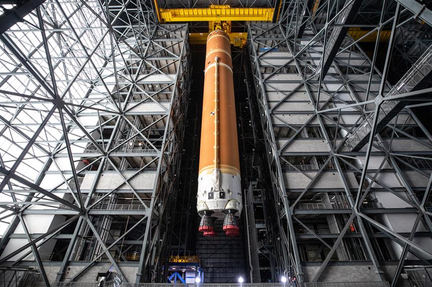 The core stage of the SLS rocket hangs from a crane.