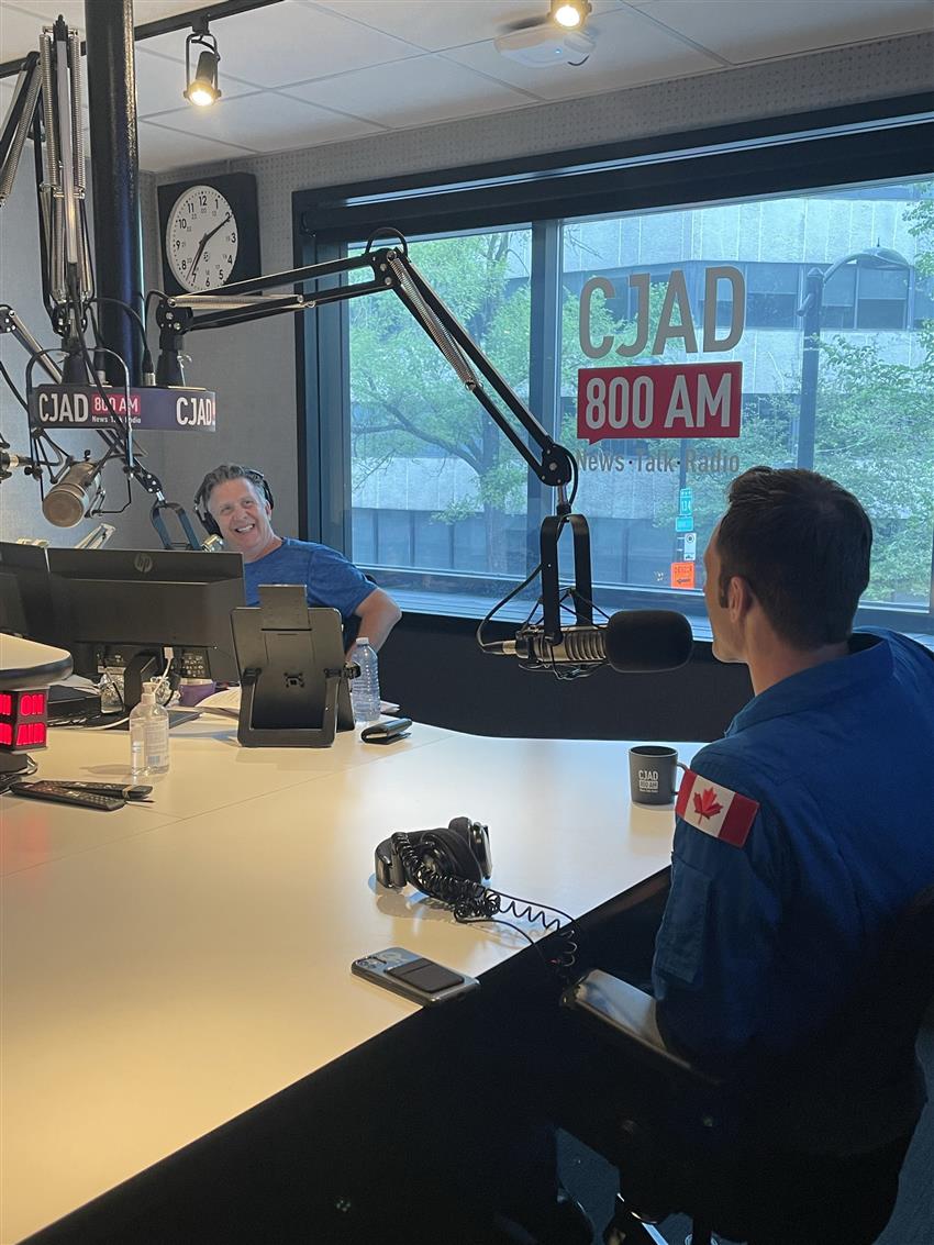 In a studio, Joshua talks with the radio host.