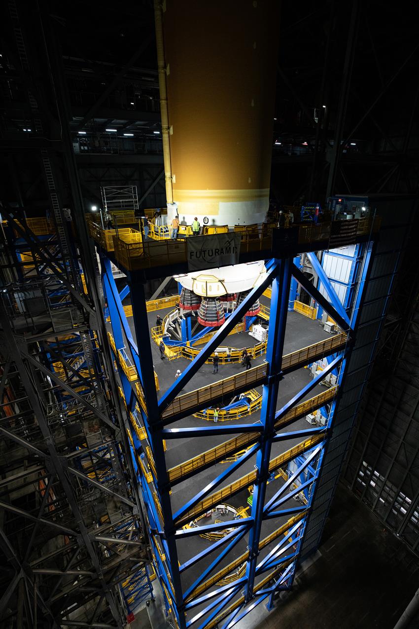 The core stage of the rocket is lowered by a crane into a metallic structure.