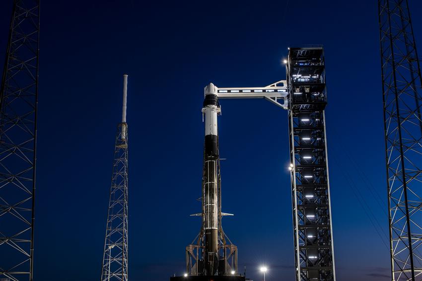 A Falcon 9 rocket carrying a Dragon cargo spacecraft on a launch tower.