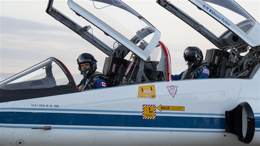 Joshua and Suni are in a T-38 jet with the canopy open.