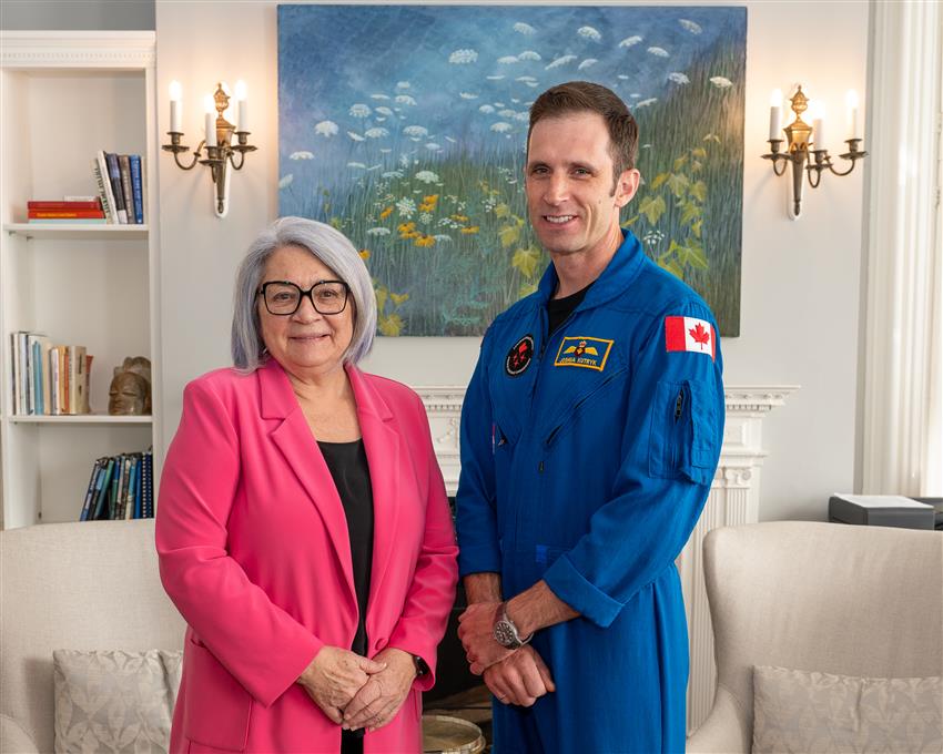 Joshua, wearing a flight suit, with Mary May Simon.