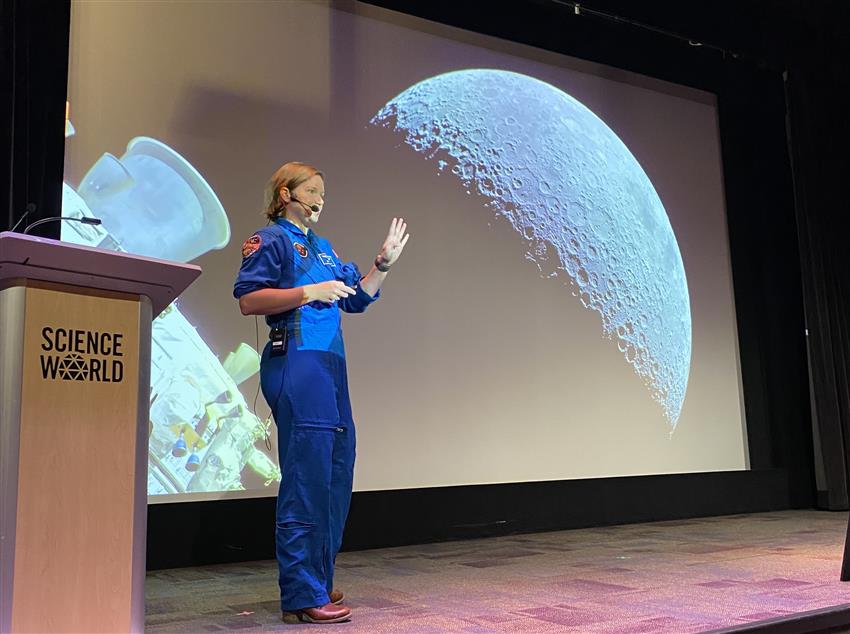 Jenni on stage with a large image of the Moon behind her.