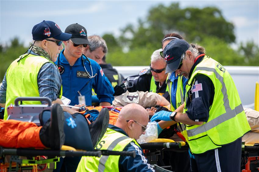 Dr. Greene looks after a patient on a stretcher alongside paramedics.