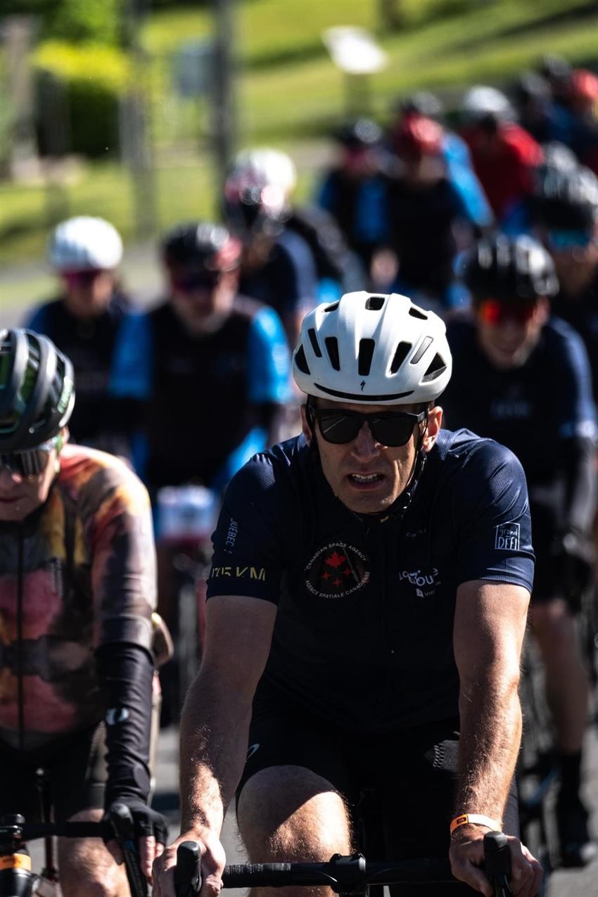 Joshua cycling with other cyclists in the background.