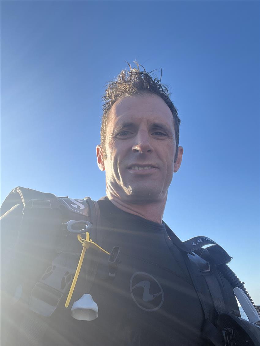 Joshua takes a selfie while wearing his wetsuit