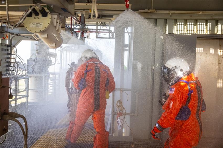 Three people walking through water being sprayed from the ceiling. 