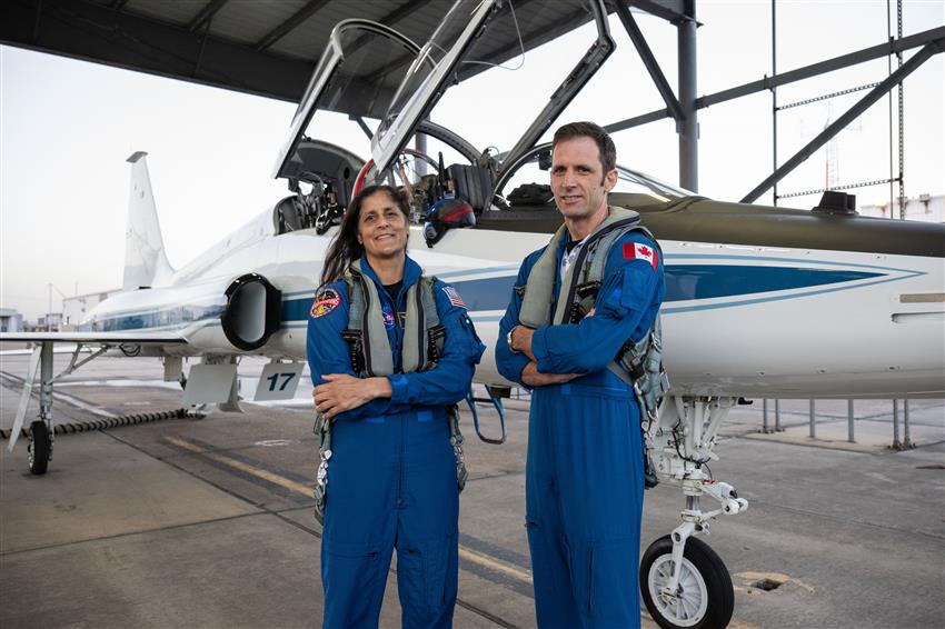 Joshua and Suni pose in front of an airplane.