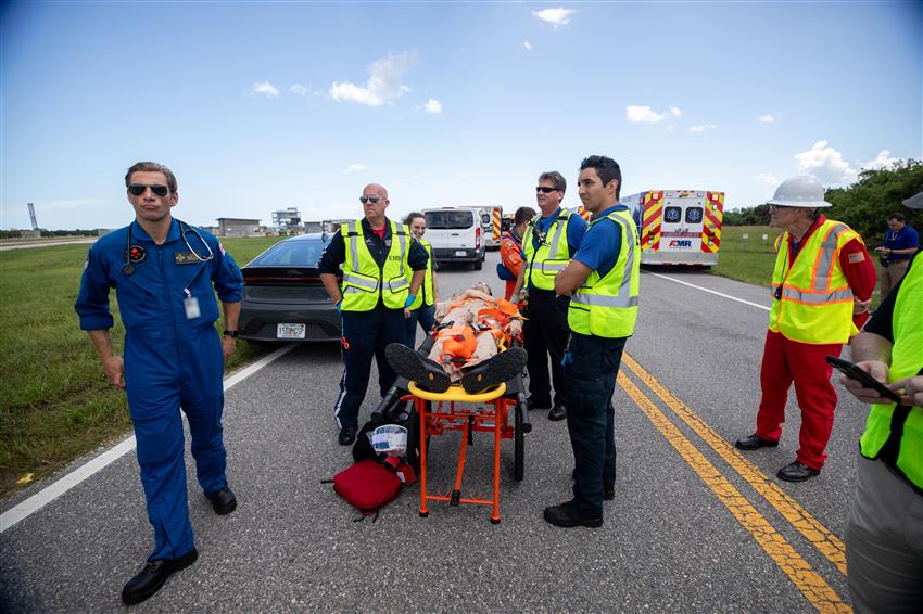 Dr. Greene with paramedics and a patient on a stretcher. Emergency vehicles in the background.