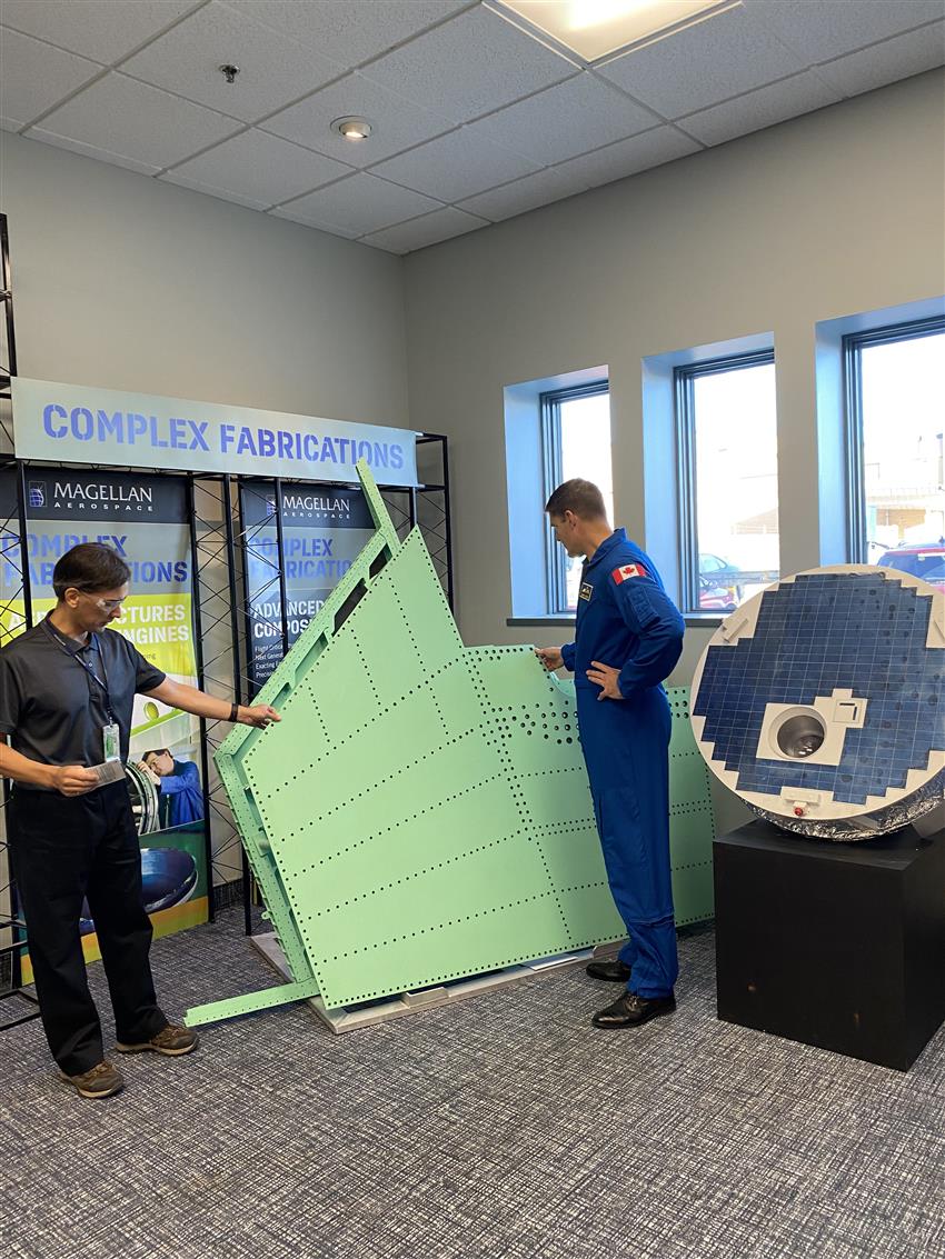 A man shows a green panel to Jeremy beside the SCISAT model.