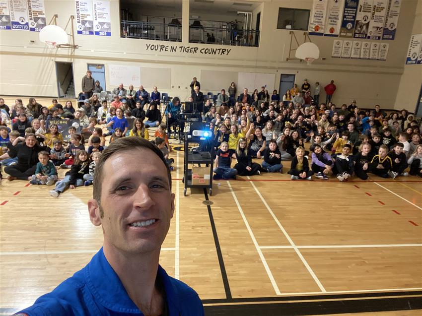 Joshua takes a selfie with students and teachers behind him.