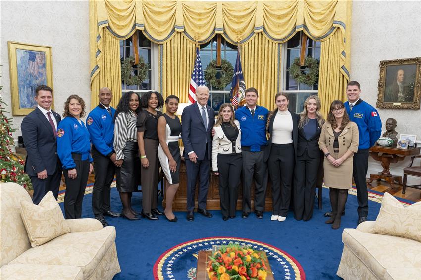 The four astronauts and members of their families pose with Joe Biden in the Oval Office.